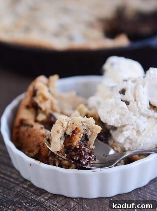 Irresistible Egg-Free Skillet Chocolate Chip Cookie 2 A white ramekin with a a chocolate chip cookie dessert next to a scoop of ice cream.