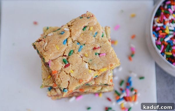 Ultimate Chewy Funfetti Blondies 3 Colorful sprinkle-filled blondie bars stacked on each other on parchment paper, ready to be served.