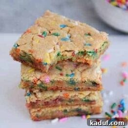 Ultimate Chewy Funfetti Blondies 4 A top-down view of a stack of golden brown funfetti blondie bars, topped with colorful sprinkles.
