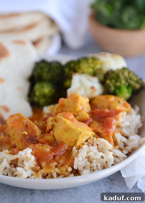 Delicious Pressure Cooker Chicken Curry with Rice A white bowl of rice topped with chicken curry and vegetables.