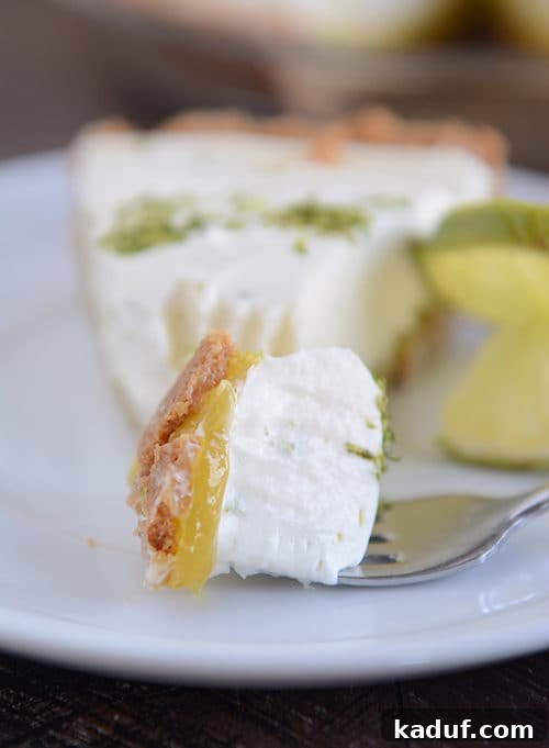 Decadent Key Lime White Chocolate Cheesecake 2 A perfectly portioned slice of Key Lime White Chocolate Cheesecake Pie, with a fork poised to take a delicious bite.