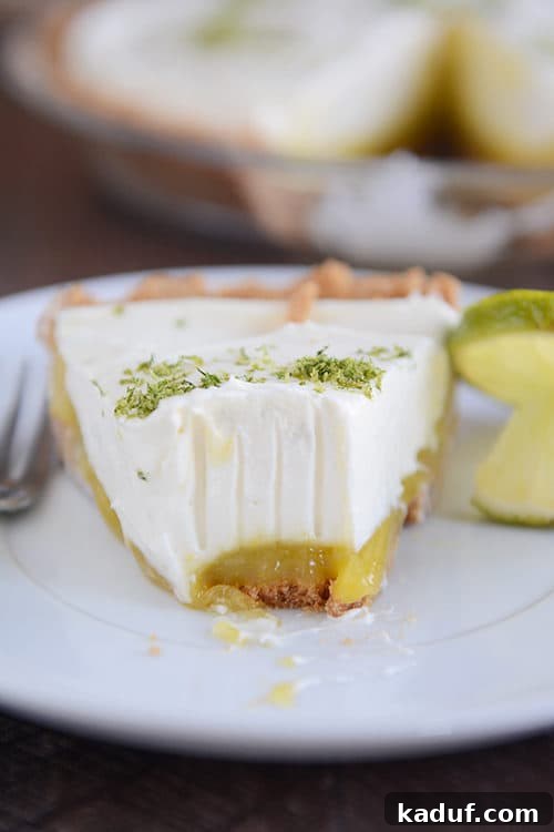 Decadent Key Lime White Chocolate Cheesecake 4 A close-up of a slice of Key Lime White Chocolate Cheesecake Pie on a white plate, revealing its distinct layers of crust, lime curd, and creamy cheesecake.