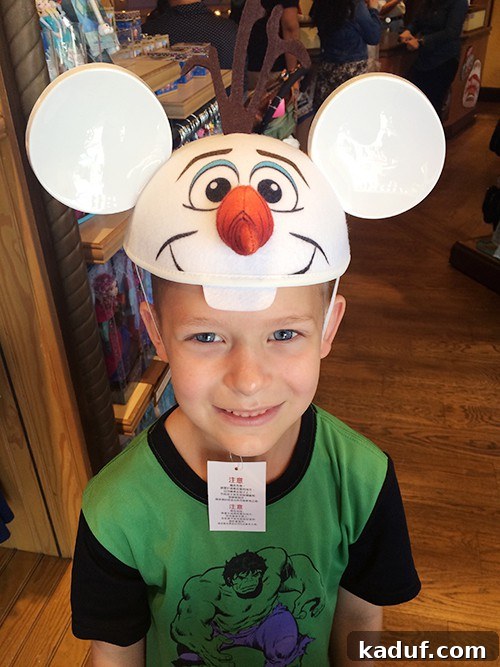 The Chill Girl's Disneyland Playbook 13 A young boy happily wearing an Olaf hat with Mickey Mouse ears at Disneyland.