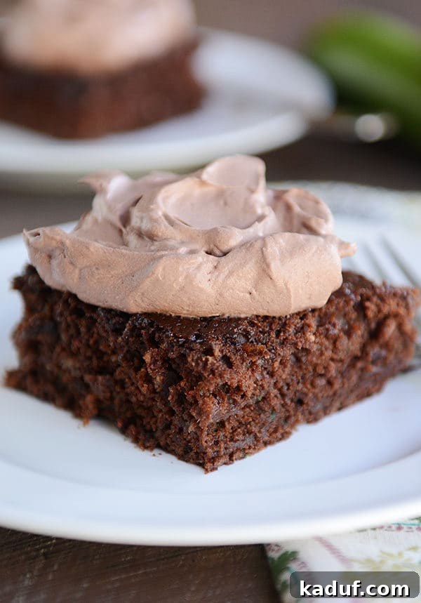 Ultimate Chocolate Zucchini Indulgence 2 A generous slice of the best chocolate zucchini cake, topped with a large dollop of fluffy whipped chocolate frosting, ready to be enjoyed.