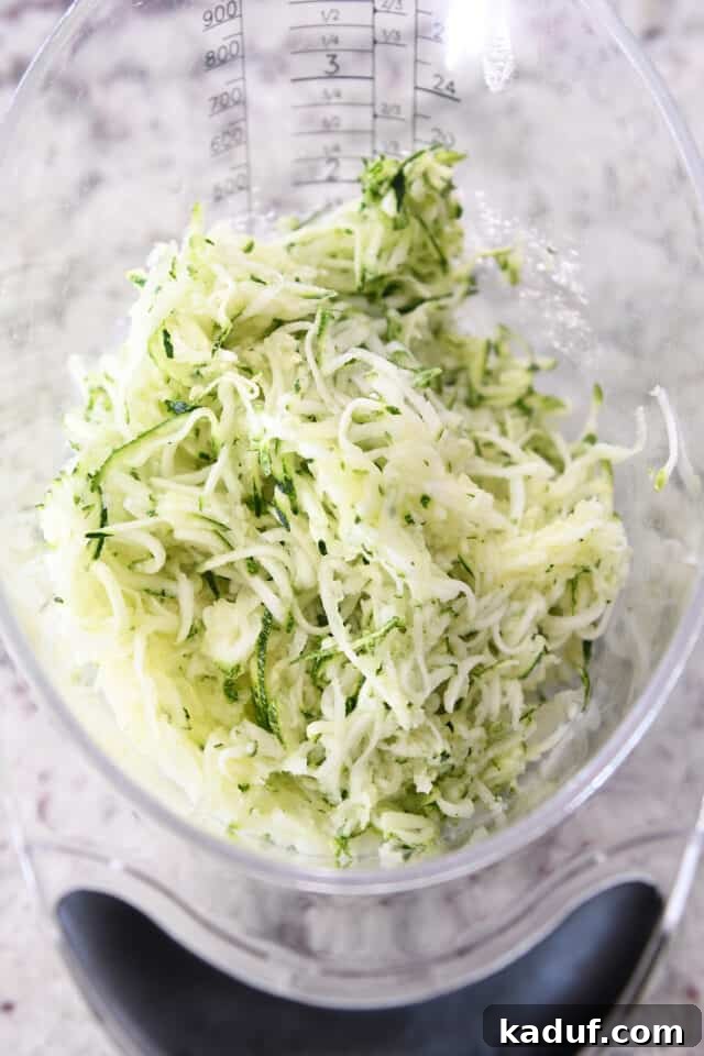 Ultimate Chocolate Zucchini Indulgence 3 A liquid measuring cup filled precisely to the two-cup mark with finely shredded fresh zucchini, showcasing the perfect amount for the cake.