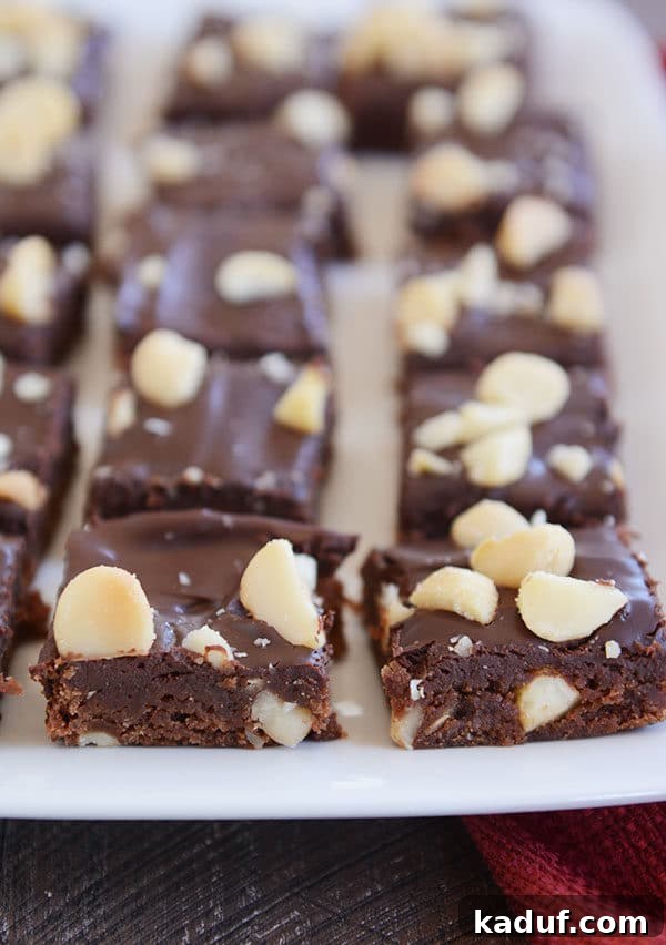 Hawaiian Chocolate Macadamia Brownies 2 A beautiful white platter overflowing with rich, chocolate macadamia nut brownies, perfectly cut and ready to be devoured. Each brownie glistens with a delectable fudge topping.