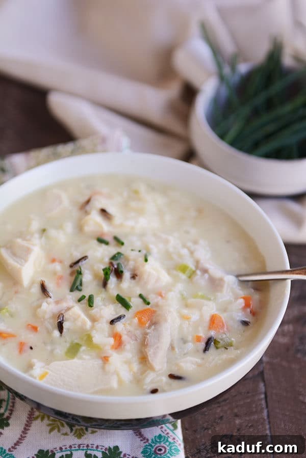 Hearty Creamy Chicken and Wild Rice Soup 5 A close-up view of a white bowl brimming with creamy chicken and wild rice soup, highlighting its rich texture and inviting steam.