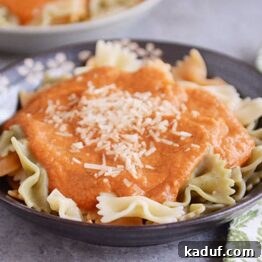 A top-down view of a serving of Harvest Pasta Sauce with bowtie pasta and a sprig of fresh herb.