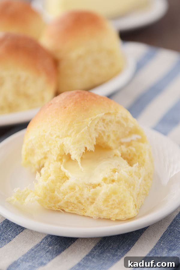 Golden Cloud Cornbread Dinner Rolls 3 A cornmeal roll split in half with a pat of butter in the middle.