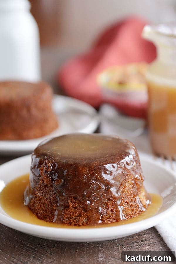 Gloriously Sticky Toffee Pudding Cake 4 A small, brown cake covered in a light brown sticky toffee sauce. The cake is glistening with the rich sauce, ready to be enjoyed.