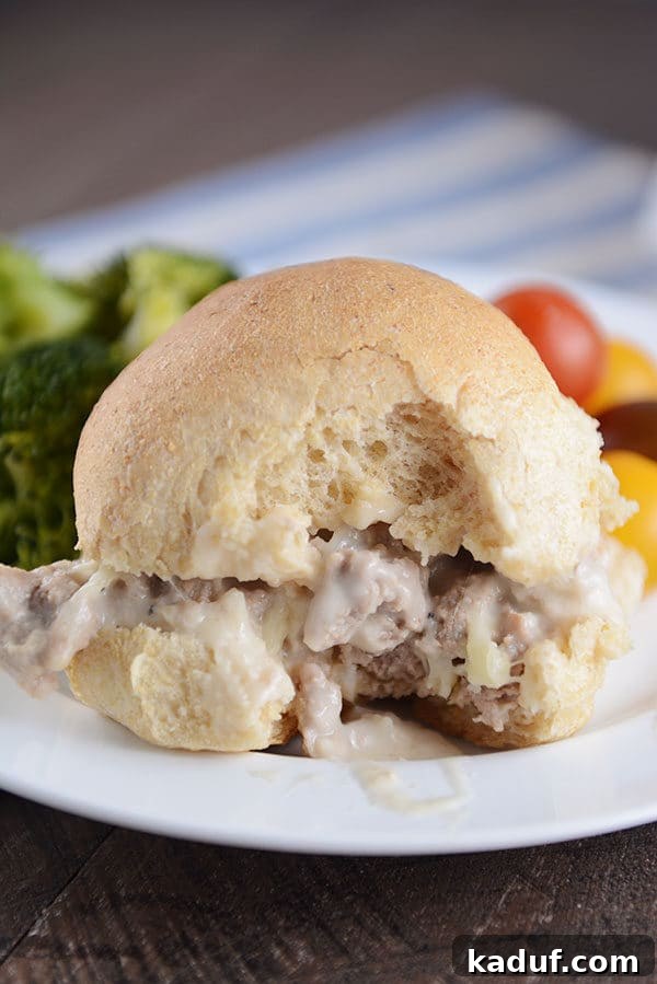 A cheesy turkey sloppy joe on a homemade bun with a bite taken out. 