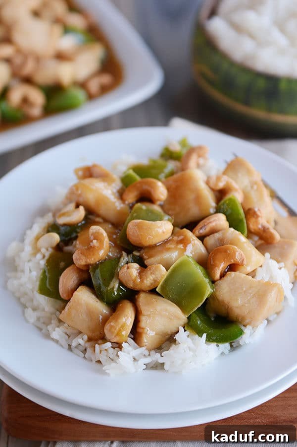 Easy 30-Minute Cashew Chicken 3 A generous serving of fluffy white rice topped with saucy cashew Chinese chicken, featuring bright green bell peppers and whole cashews.