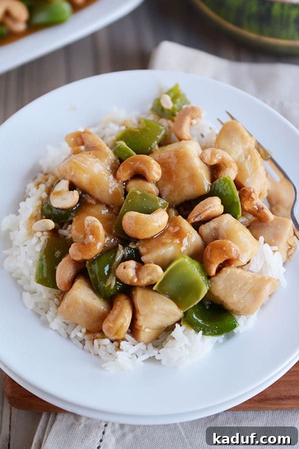 Easy 30-Minute Cashew Chicken 5 Top view of a white plate with perfectly cooked rice topped with a generous portion of Chinese cashew chicken, ready to be served.