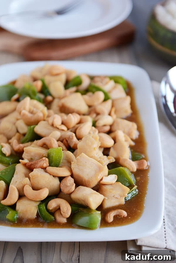 Easy 30-Minute Cashew Chicken 6 A white platter filled with saucy cashew chicken, generously mixed with large green bell pepper chunks, ready to be served.