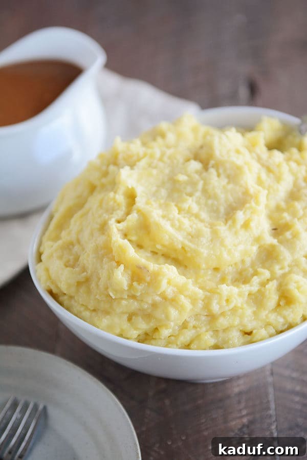 Velvety Instant Pot Mashed Potatoes 2 Large bowl full of mashed potatoes, with a gravy boat of brown gravy next to it.