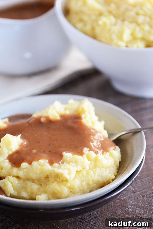 Velvety Instant Pot Mashed Potatoes 5 A bowl full of mashed potatoes topped with brown gravy.
