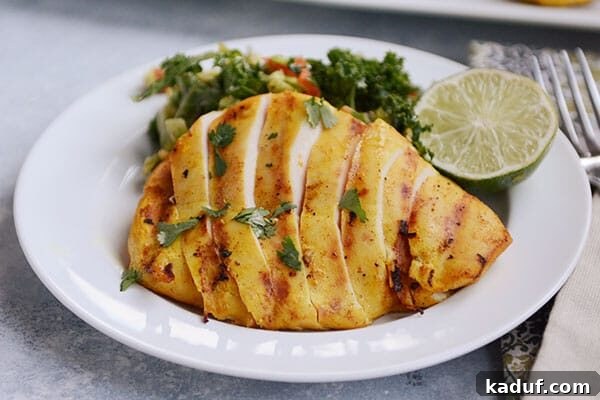 Creamy Thai Coconut Grilled Chicken 3 A white plate with sliced grilled chicken and a green salad and slice of lime on the plate.