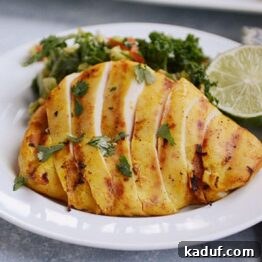 Grilled Thai Coconut Milk Chicken slices on a plate with fresh greens.