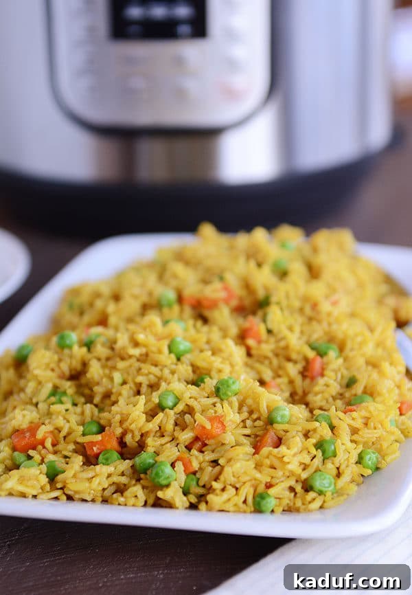 Instant Pot Indian Veggie Pulao 2 A white plate full of flavorful Indian Vegetable Rice, featuring tender peas and carrots, with an Instant Pot visible in the background.