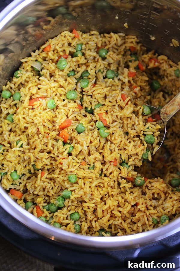 Instant Pot Indian Veggie Pulao 3 An Instant Pot bowl filled with perfectly cooked, yellow-tinted Indian Vegetable Rice, generously mixed with vibrant peas and carrots.