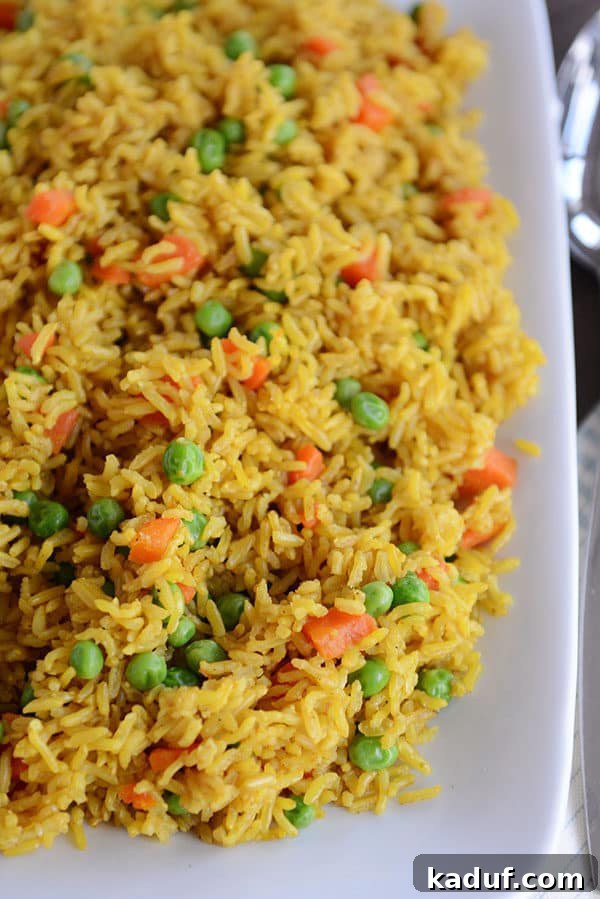 Instant Pot Indian Veggie Pulao 5 A white platter showcasing a generous serving of vibrant Indian Vegetable Rice, flecked with bright peas and finely diced carrots.