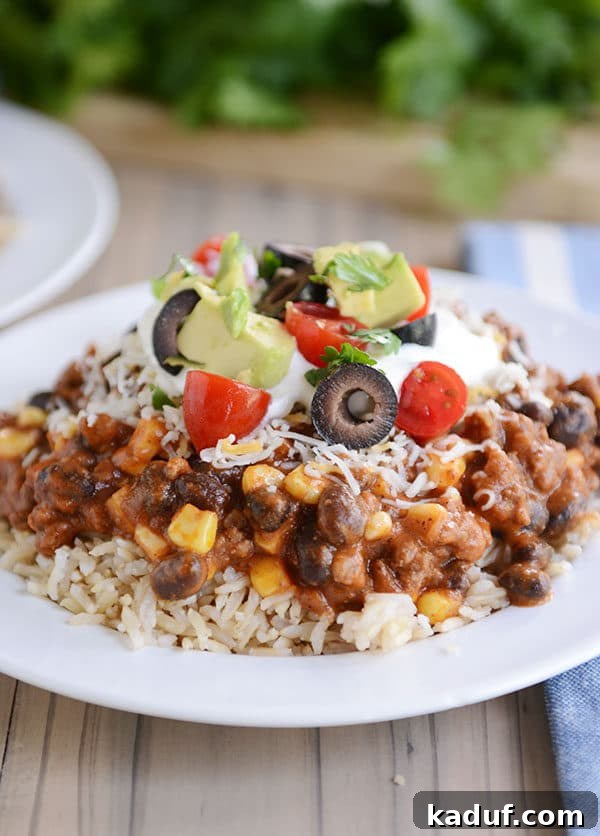 Easy 30-Minute Mexican Haystacks 2 A white plate of cooked rice topped with a Mexican beef and corn mixture, tomato, olive, avocado, and sour cream. This colorful dish is the perfect easy weeknight meal.