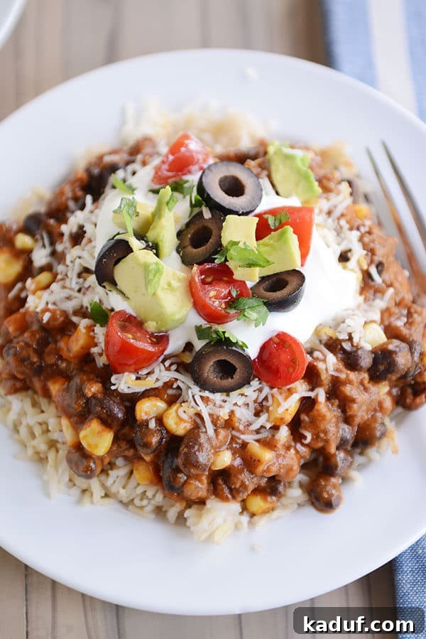 Easy 30-Minute Mexican Haystacks 3 Top view of a white plate of cooked rice topped with a beef and corn mixture and taco toppings.