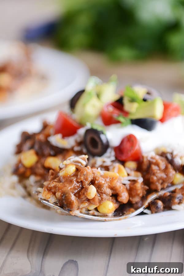Easy 30-Minute Mexican Haystacks 4 A fork taking a bite of Mexican haystack off a white plate of topping-covered haystack..