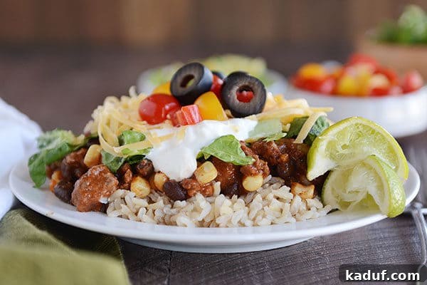 Easy 30-Minute Mexican Haystacks 6 A white plate of cooked rice topped with a beef Mexican haystack mixture topped with taco toppings.