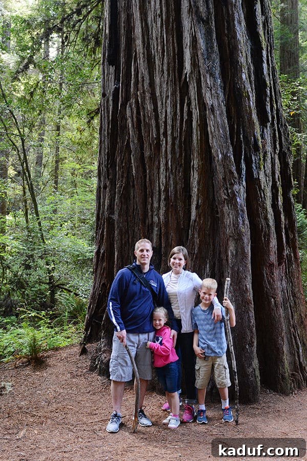 The Laid-Back Guide to Redwood National Forest 25 A Mom, Dad, and two kids standing in front of a large Redwood tree in Stout Grove, emphasizing its scale.