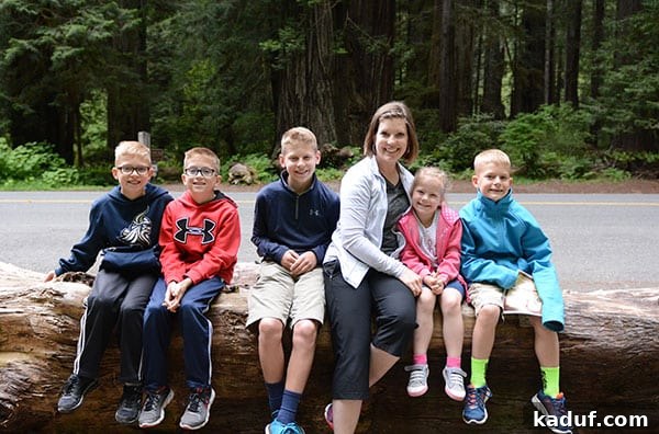 The Laid-Back Guide to Redwood National Forest 7 A Mom sitting on a log with her five kids in the redwood forest.