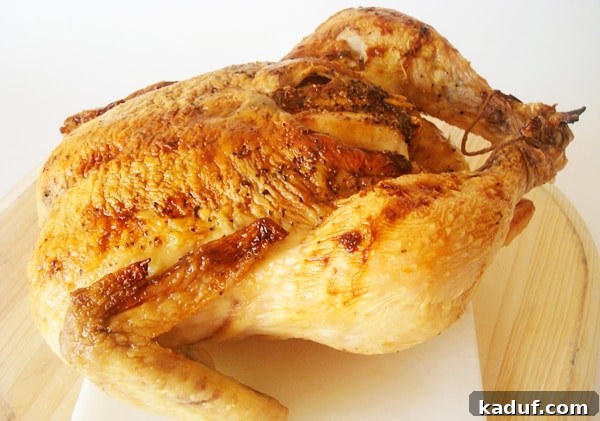Golden Honey Roasted Chicken 2 Whole roasted chicken on a white cutting board, garnished with fresh herbs and a golden-brown, crispy skin.