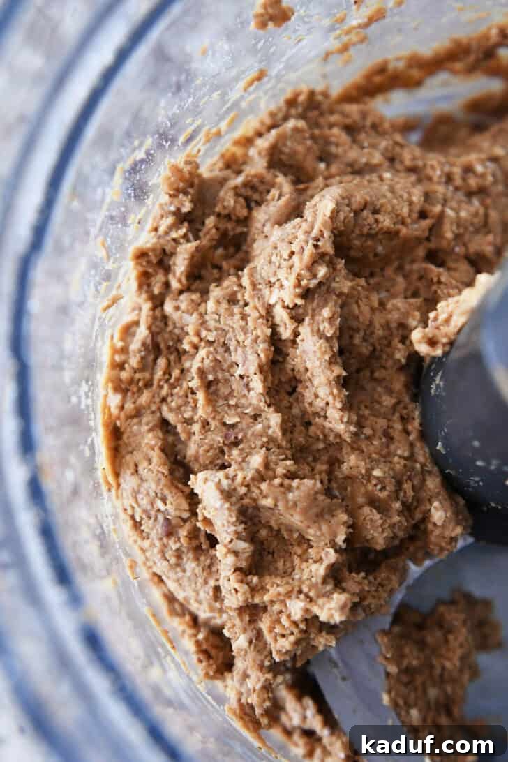 Delicious Protein Bites: Tailored to Your Taste 4 Top-down view of a smooth peanut butter and oat mixture after being processed, forming a cohesive dough.