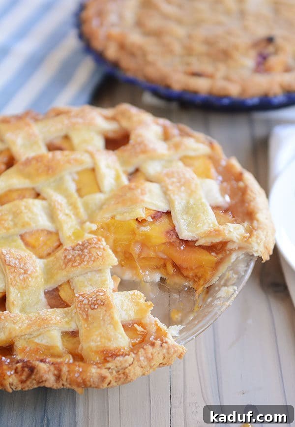 Summertime Peach Pie Perfection 4 A delicious fresh peach pie with a lattice top, showing one slice expertly removed, highlighting the juicy peach filling within the flaky crust.
