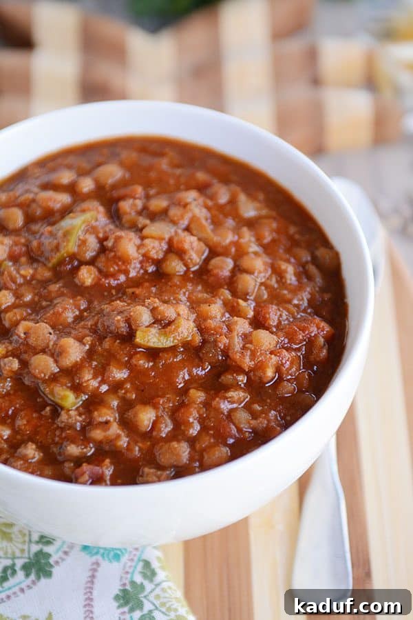 A top-down view of a single white bowl filled with flavorful lentil beef chili, ready to be topped.