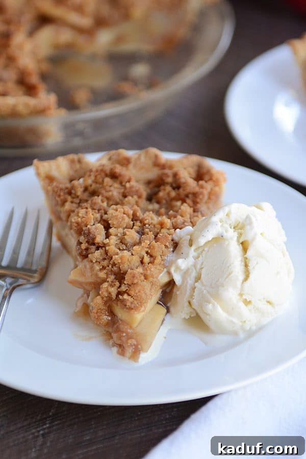 Simple Apple Crumble Pie 2 A generous slice of warm apple crumble pie, perfectly golden brown and topped with a scoop of creamy vanilla ice cream, beckoning to be enjoyed.