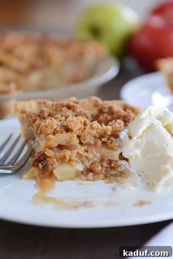 Simple Apple Crumble Pie 5 A single slice of apple crumble pie with a delicious bite taken out, served alongside a melting scoop of vanilla ice cream.