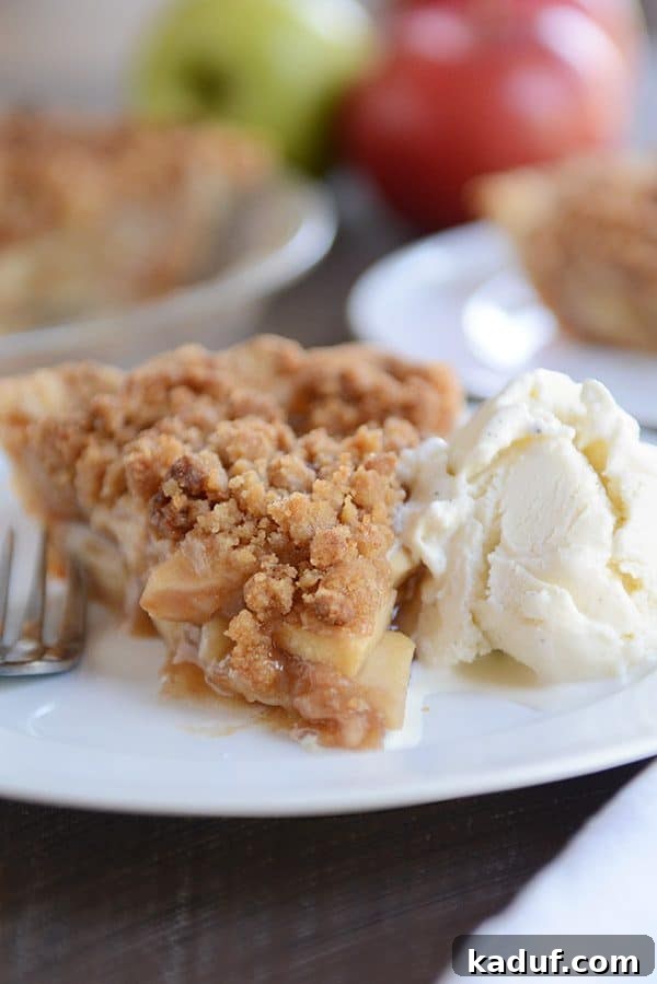 Simple Apple Crumble Pie 6 A beautifully plated slice of apple crumble pie and a scoop of vanilla ice cream on a clean white plate, ready to be enjoyed.