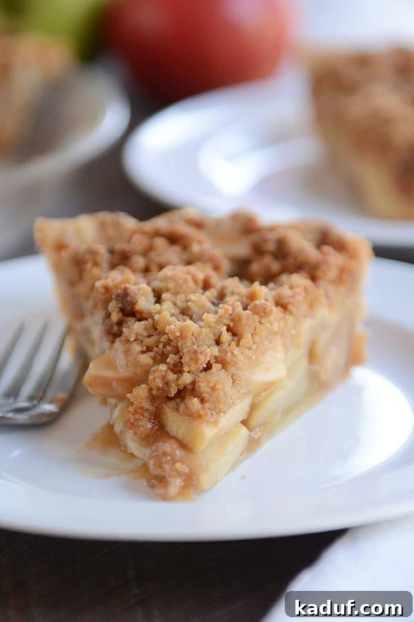 Simple Apple Crumble Pie 7 A solitary, perfectly baked piece of apple crumble pie rests on a simple white plate, inviting a taste.