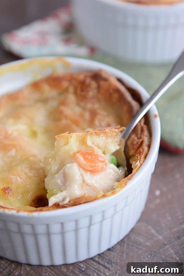 Savory Chicken or Turkey Pot Pie Perfection 4 A small white ramekin of chicken pot pie with a spoon scooping a generous bite.