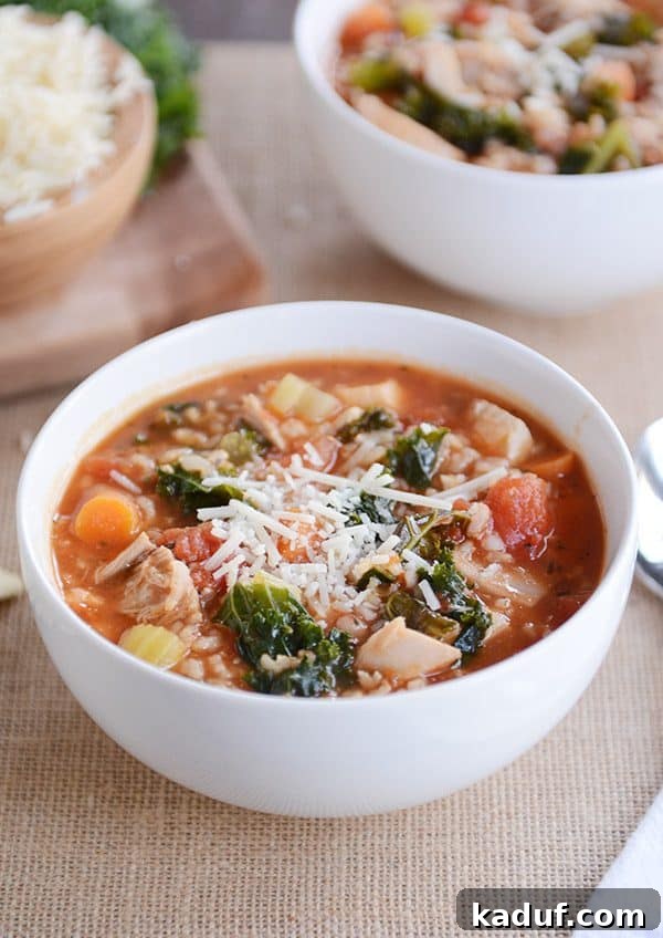 Versatile Poultry and Brown Rice Soup 2 A white bowl full of turkey, vegetable, and brown rice soup topped with parmesan cheese, ready to be enjoyed.