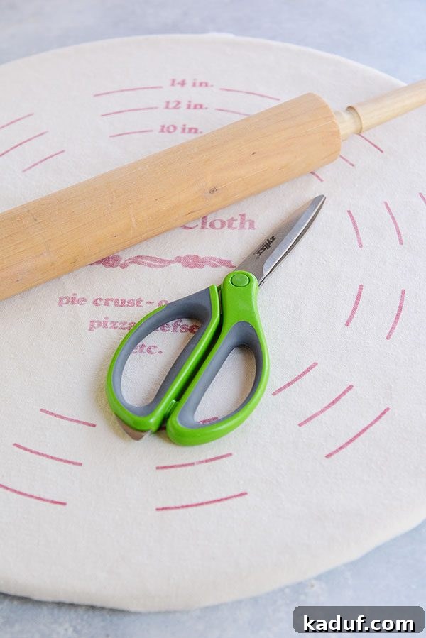 Pie Boot Camp: Gearing Up for Great Pies 6 Scissors and a wooden rolling pin resting on a pie crust pastry cloth, highlighting useful tools for dough preparation.