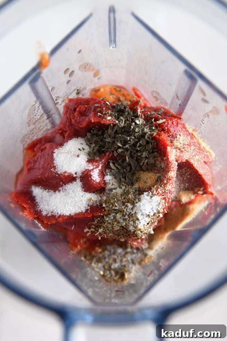 Effortless Homemade No-Cook Pizza Sauce 4 A blender filled with tomato paste, basil, oregano, garlic salt, and sugar, waiting to be processed.