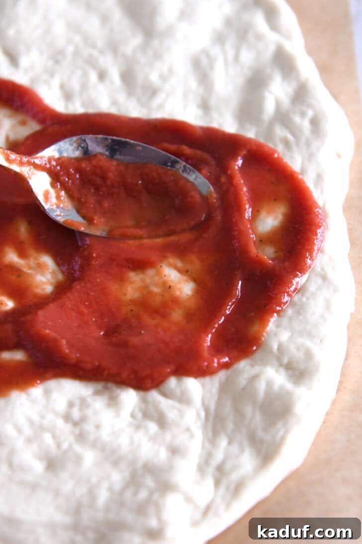 Effortless Homemade No-Cook Pizza Sauce 6 Spreading smooth, red pizza sauce evenly over fresh pizza dough.