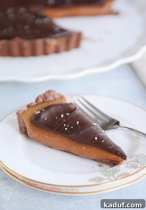 Rich Chocolate Caramel Tart 3 A perfectly sliced piece of chocolate caramel tart resting on a white plate, highlighting its smooth caramel and ganache layers.