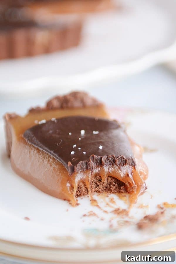 Rich Chocolate Caramel Tart 5 A close-up of a chocolate caramel tart slice with a small bite taken out, showing the creamy caramel interior.