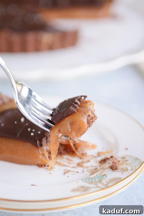 Rich Chocolate Caramel Tart 6 A fork lifts a bite of rich chocolate caramel tart, showcasing the sticky, golden caramel and dark chocolate.