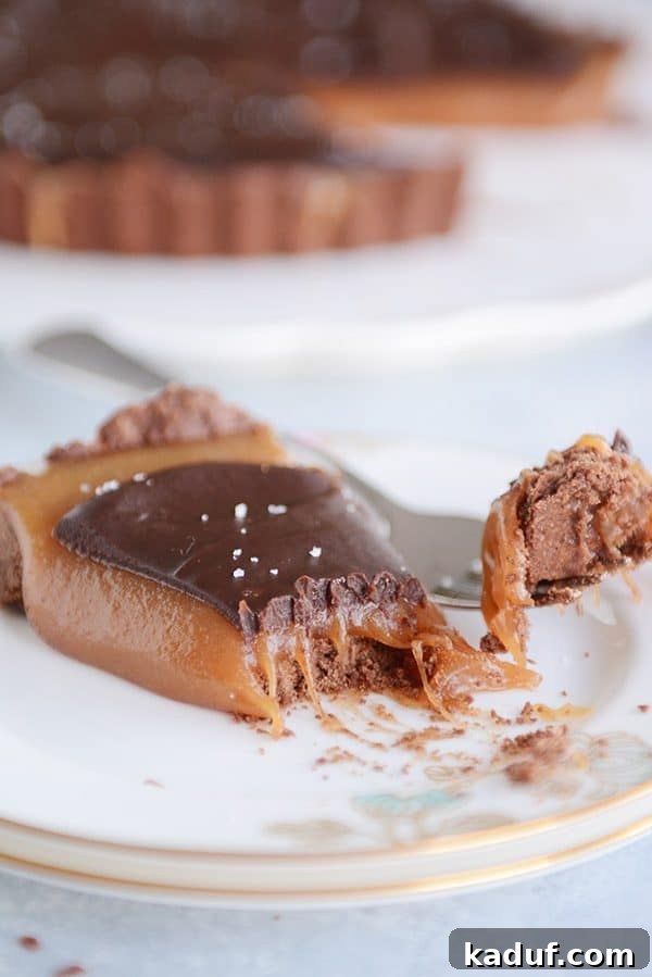 Rich Chocolate Caramel Tart 7 A close-up shot of a single slice of chocolate caramel tart, with a fork gently taking a bite, emphasizing the soft texture of the caramel.