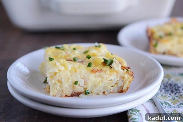 Rich Cheesy Hash Brown and Egg Overnight Bake 8 A piece of cheesy egg and hash brown casserole on a white plate.