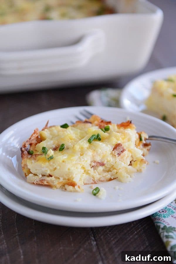 Rich Cheesy Hash Brown and Egg Overnight Bake 5 A piece of cheesy egg and hash brown casserole on a white plate, with a bite taken out.